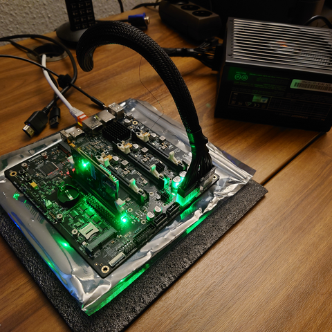 A powered on Turing Pi 2 board. It is connected to a BeQuiet! power supply.

The first slot is populated with a CM4 module.

There are a number of LEDs shining in comforting green.