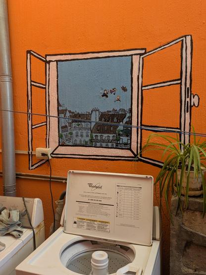 A window painted on an orange wall in a laundry room. The window is inspired from a JJ Sempé cartoon, with Paris roofs and three persons and a dog flying over Paris.