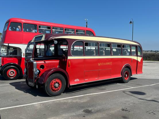 An old red half cab single deck bus. The side has “Wilts and Dorset” painted on it.