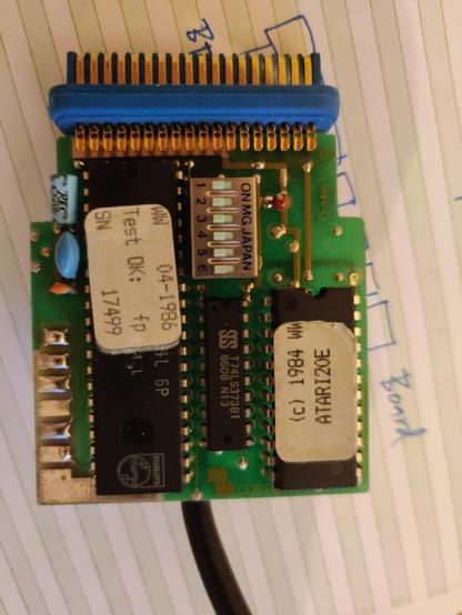 The business side of the little board in the Centronics connector. Three of the chips have stickers on them which I'm loath to remove. The 24-pin DIP chip has a sticker with the text "(c) 1984 WW ATARI20E". The 40-pin DIP has a sticker with the legend "WW 04-1986 Test OK: fp SN 17499".