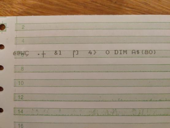 A close up if a line of garbage printed on green bar paper.

Most of the characters printed are not even in the ATASCII character set. At the end of the line is some valid text "0 DIM A$(80)"