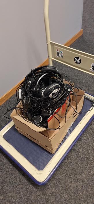 Un chariot sur lequel un carton est rempli de casque-micros.