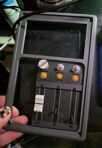 Part of a 3D printed device with three faders three knobs and three buttons, up top is a space for a LCD screen.