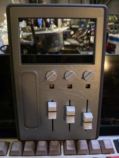 Part of a 3D printed device with three faders three knobs and three buttons, up top is a space for a LCD screen.