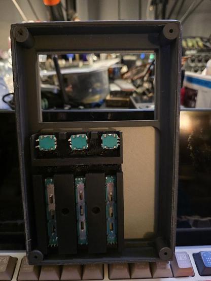 The open rear 3D printed device with three faders three knobs and three buttons, up top is a space for a LCD screen.