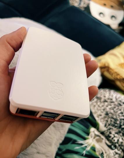 A photo of my hand holding a Raspberry Pi in a white case