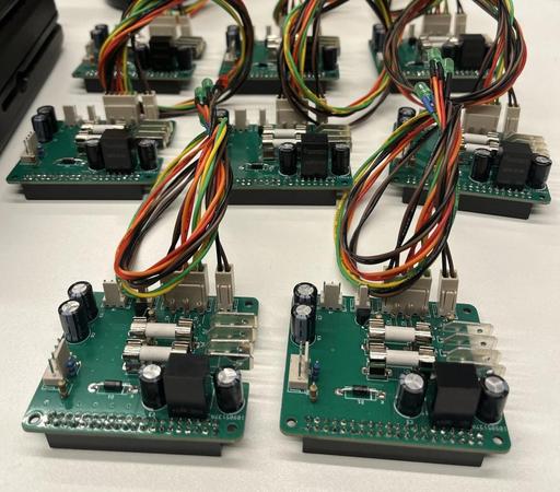 Eight green boards populated with all sorts of electronic components and neat bundles of colorful wires.
