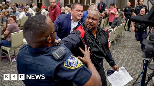 A protester resists being removed by police officer at town hall