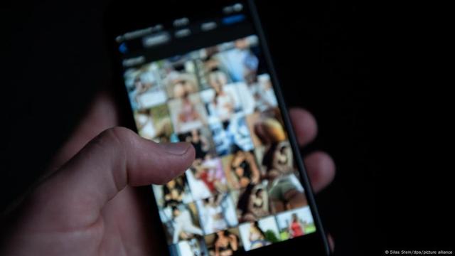 A hand holds a phone with pictures of women. | Image: Silas Stein/dpa/picture alliance