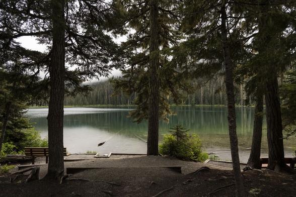 The first lake is quiet and empty at Pipi7íyekw / Joffre Lakes. It's an overcast day in June, but the water is still green under the clouds.