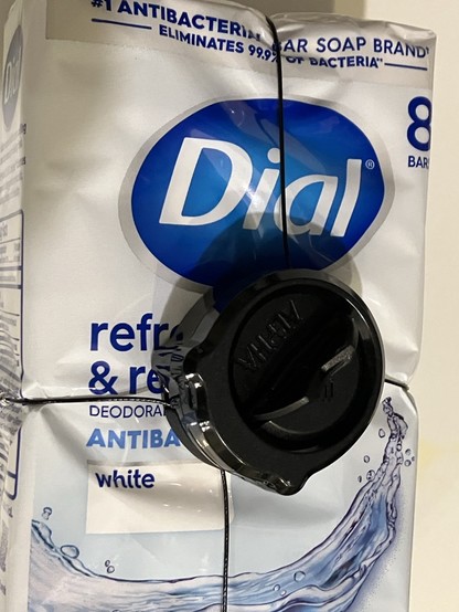 A package of Dial soap bars with a Spider Wrap anti-theft device wrapped around it.