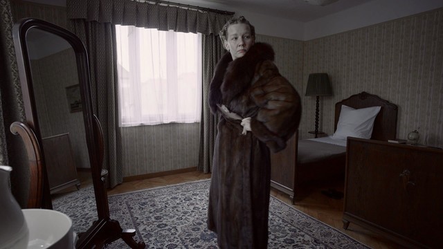 A movie still depicting that chilling moment when Hedwig Höss tries on a mink coat without stopping for even a moment to consider who it used to belong to or how it happened to come into her possession. Later on when she threatens a servant, it’s clear she knows exactly what happens on the other side of Auschwitz, which can be seen from the back yard of her villa.