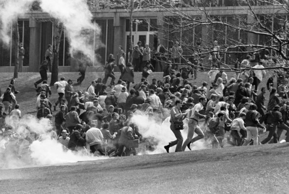 Hundreds of Kent State University students, including anti-war demonstrators, flee as National Guardsmen fire tear gas and bullets into the crowd on a grassy hillside.