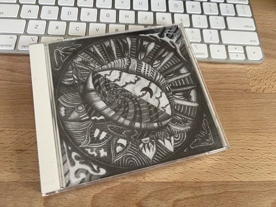A photo of the cover art which is a trippy charcoal painting in black-and-white by Christoph Heemann that looks like a tear in the sky in the style of a Native American painting.