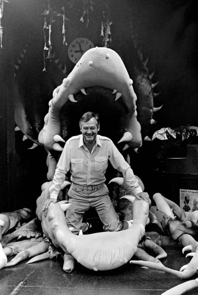 A black-and-white photo of Roger Corman on the set of The Little Shop of Horrors (1960). He’s standing in the mouth of Audrey Jr., the hybrid plant with an insatiable appetite for blood.