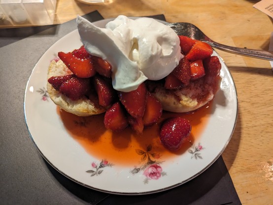 A biscuit split in half. 

Macerated strawberries and the juice from the maceration test on top of the halves 

A large dollop of whipped cream rests atop the strawberries.
