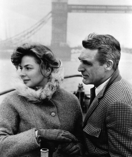 A closer view of Ingrid Bergman (left) and Carey Grant (right) wearing warm coats while standing on the deck of a boat.