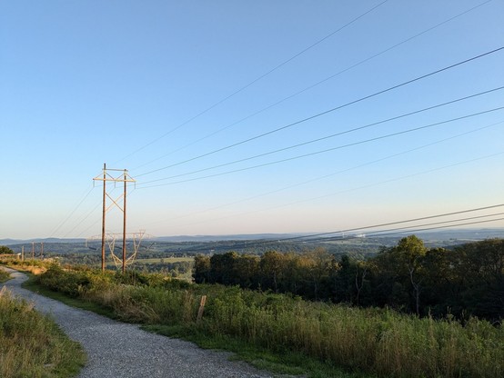 Scenic overlook at Rocky Ridge Park in York County, PA. Gravel trail in a natural field. High voltage lines in the medium distance, rolling hills of York County beyond.