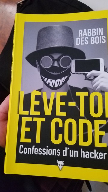 Couverture du livre «Lève-toi et code» de Rabbin des bois. Le sous-titre est «Confession d'un hacker».

On voit une personne avec un chapeau au de forme, des lunettes de soudure, un masque chirurgical décoré d'un grand sourire et de dents pointues. 

Il porte un telephone sur sa tempe comme comme s'il se suicidait.