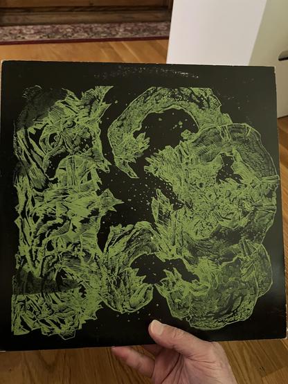 A green hand silkscreened image that looks like a Bonnie Banks drawing on a black LP jacket. White labels on vinyl without any info or etching near the runout.