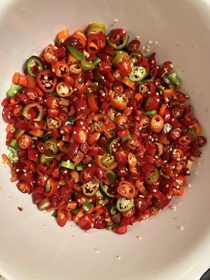 A batch of (mostly) ripe red chile peppers have been sliced into a bowl. Most here are buena mulata, there are also jalapeños, Hungarian blacks, a few lemon dreams, a few atris, and a lone Ajvarski. Ready to cook!