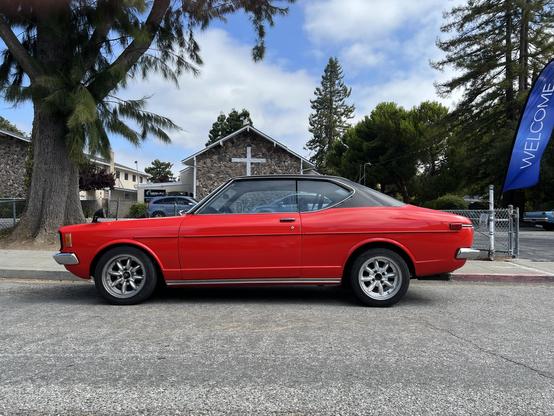 I think it’s an old Datsun from the 70s with side view mirrors on the hood. Beautiful two-tone paint job with red body and black on top.