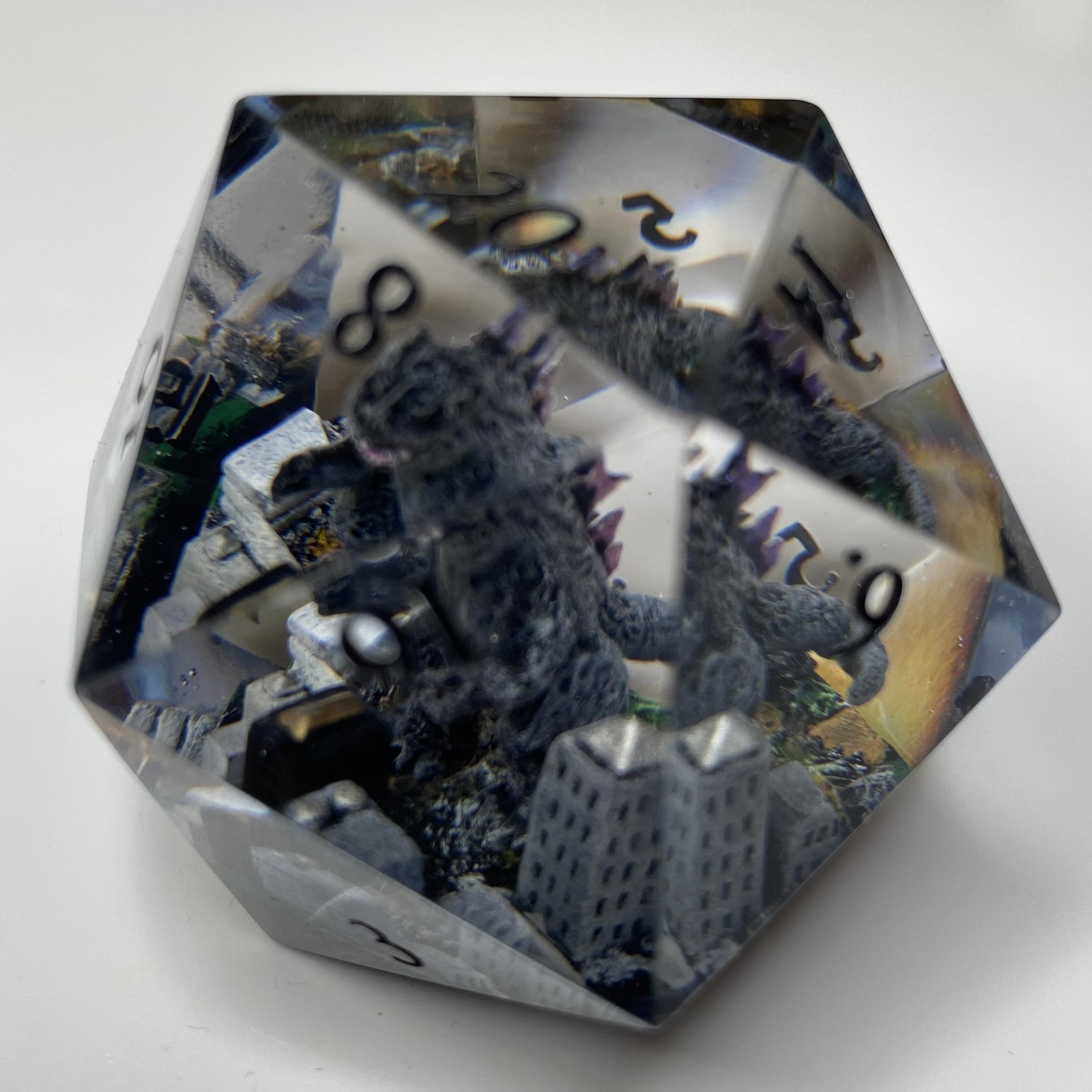 Godzilla standing in and over a partially destroyed city, inside a clear resin 40mm d20