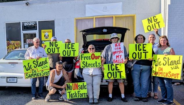 Activists stand outside Da Sammich Spot on Park Avenue in historic Orange Mound, Memphis, Tennessee. They're holding signs with slogans like
"ICE OUT" "No UNsafe Task Force" and "We Stand With Da Sammich Spot"