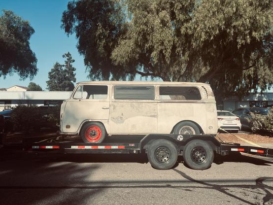 THIS is a 1972 T2b Volkswagen Kombi bus with a 1.6 L engine with dual intake ports on each cylinder head, stripped to the primer and sitting on a trailer awaiting its next step.