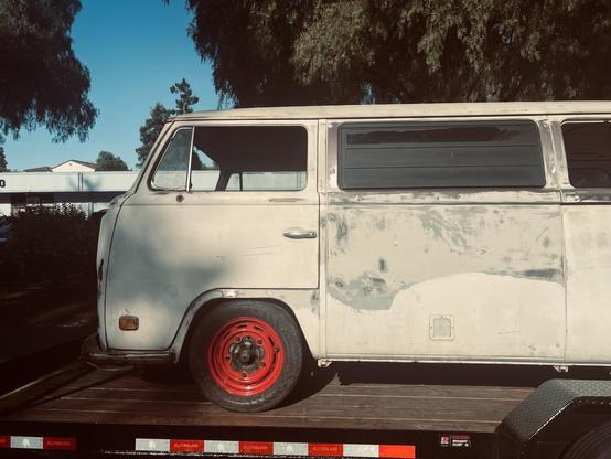Closeup of the front half of this Kombi with its distinctive red steel wheels and exposed lugs. Body is in pretty decent condition all things considered!